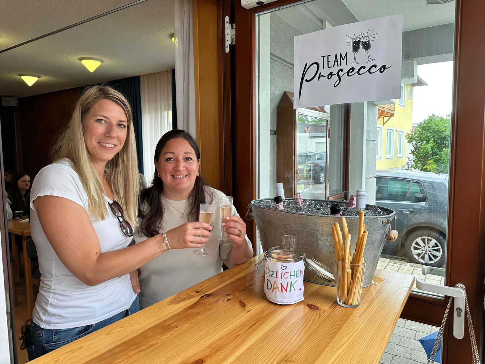 Zwei Frauen stoßen beim Prosecco-Eckerl des Dorfcafés an